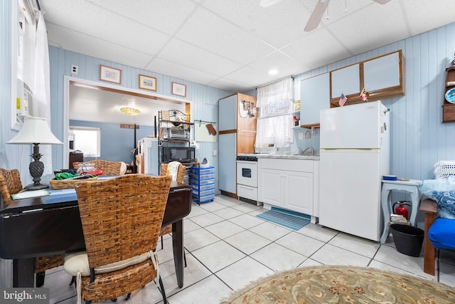 kitchen featuring ceiling fan, a drop ceiling, light tile patterned floors, and white appliances