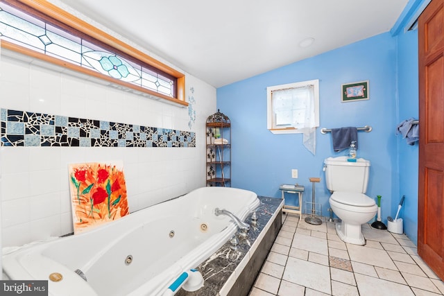 bathroom featuring tile patterned flooring, toilet, and tiled tub