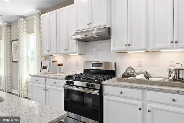 kitchen with decorative backsplash, light stone countertops, white cabinets, and stainless steel gas stove