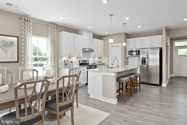 kitchen with sink, white cabinetry, decorative light fixtures, a center island with sink, and appliances with stainless steel finishes