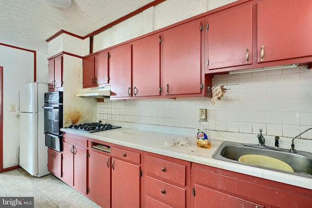 kitchen featuring backsplash, gas stovetop, sink, light tile patterned floors, and white fridge