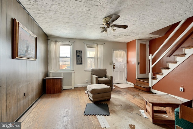 unfurnished room with ceiling fan, wood walls, and light wood-type flooring