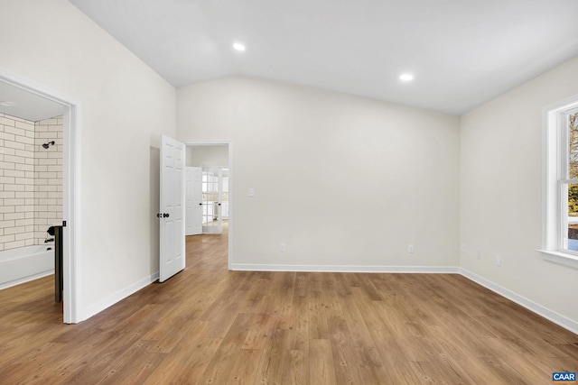 empty room with light hardwood / wood-style flooring and vaulted ceiling