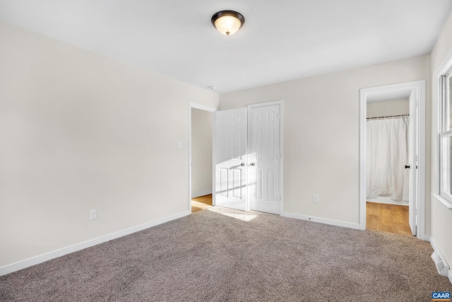 unfurnished bedroom featuring a closet, connected bathroom, and light carpet