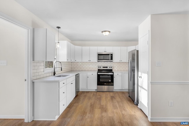 kitchen featuring white cabinetry, sink, decorative light fixtures, and stainless steel appliances