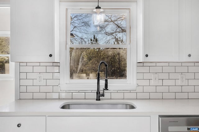 kitchen featuring pendant lighting, a wealth of natural light, sink, and white cabinets