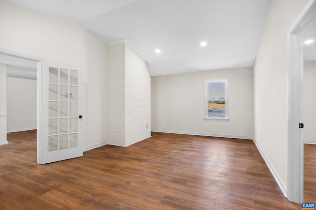 spare room featuring lofted ceiling and dark hardwood / wood-style floors