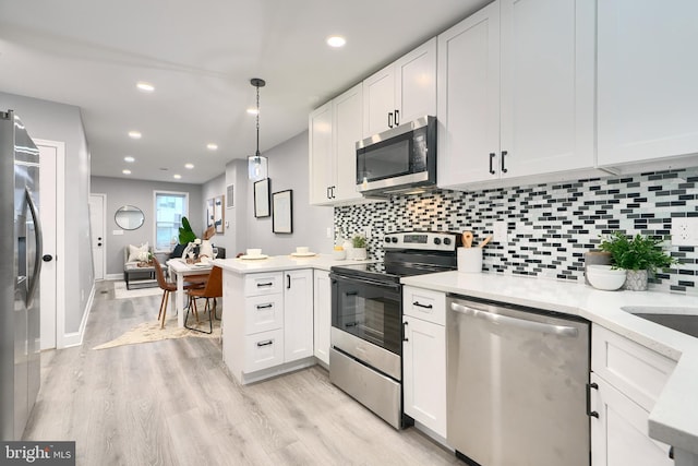 kitchen with kitchen peninsula, decorative backsplash, stainless steel appliances, white cabinetry, and hanging light fixtures