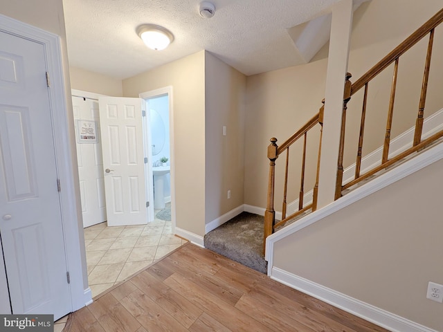 foyer entrance with light hardwood / wood-style floors and a textured ceiling