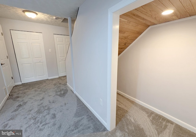 corridor featuring wood ceiling, vaulted ceiling, and light colored carpet