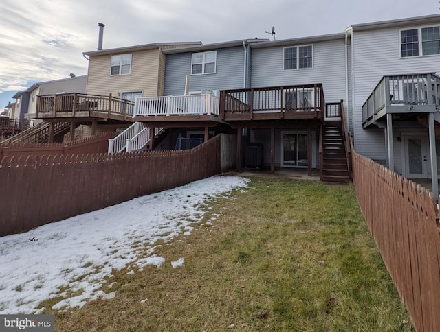 snow covered house with central air condition unit, a lawn, and a deck