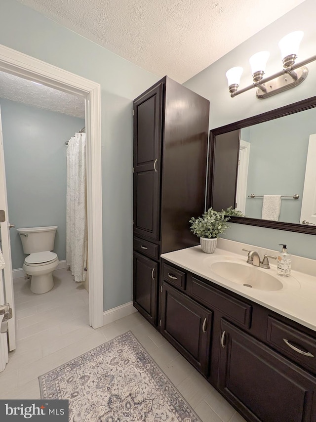 bathroom featuring toilet, a textured ceiling, tile patterned floors, and vanity