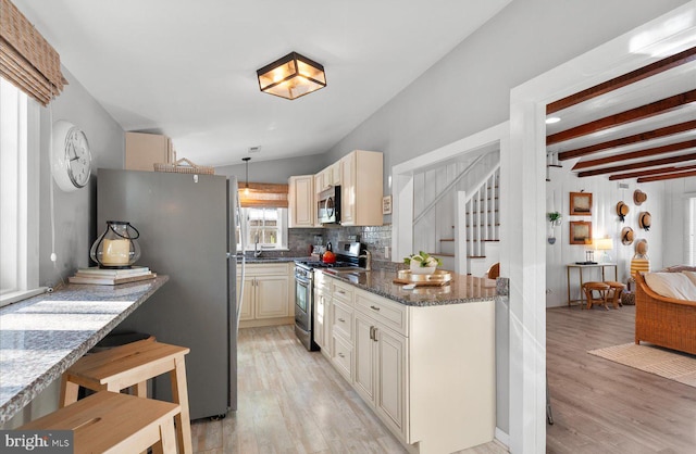 kitchen with dark stone countertops, pendant lighting, decorative backsplash, appliances with stainless steel finishes, and cream cabinets