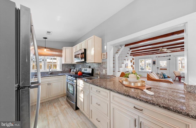 kitchen featuring appliances with stainless steel finishes, dark stone counters, tasteful backsplash, hanging light fixtures, and beam ceiling