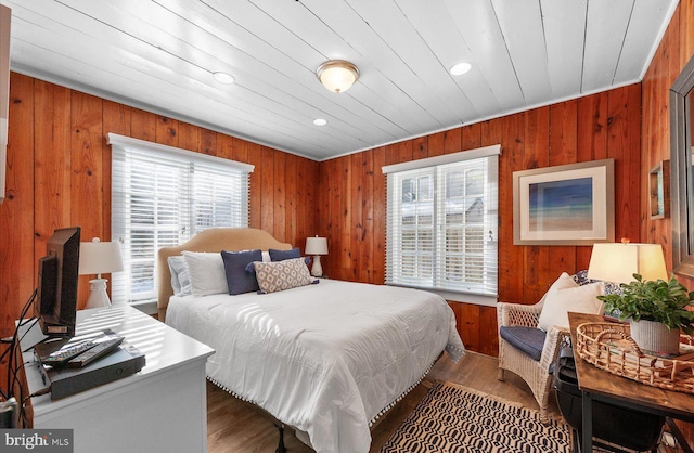 bedroom featuring wood-type flooring, multiple windows, wood ceiling, and wooden walls