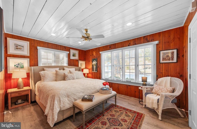 bedroom with ceiling fan, light wood-type flooring, wood walls, and wooden ceiling