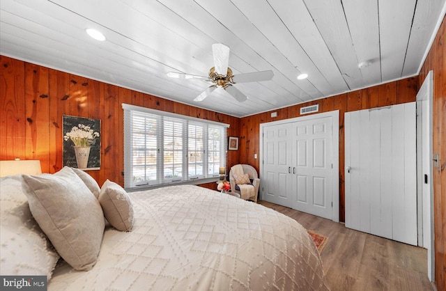 bedroom featuring ceiling fan, hardwood / wood-style flooring, and wood walls