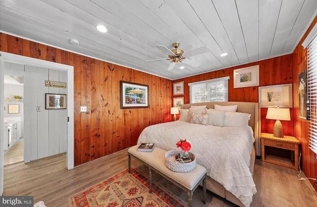 bedroom with ceiling fan, wood ceiling, light hardwood / wood-style floors, and wood walls