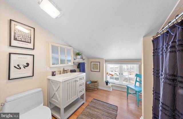 bathroom featuring toilet, lofted ceiling, hardwood / wood-style flooring, and vanity