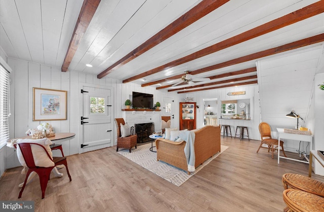 living room with a fireplace, beam ceiling, light hardwood / wood-style flooring, and ceiling fan