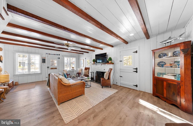 living room featuring ceiling fan, beamed ceiling, and light hardwood / wood-style floors