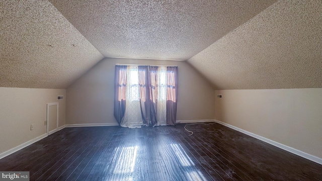 bonus room with vaulted ceiling, dark wood-type flooring, and a textured ceiling