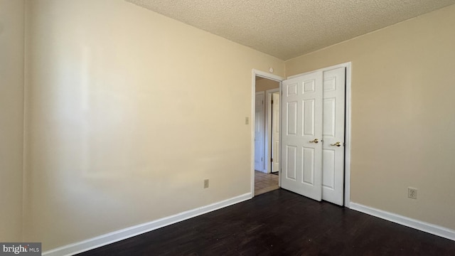 unfurnished bedroom with dark hardwood / wood-style flooring and a textured ceiling