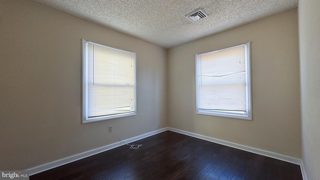 spare room featuring a textured ceiling and dark wood-type flooring