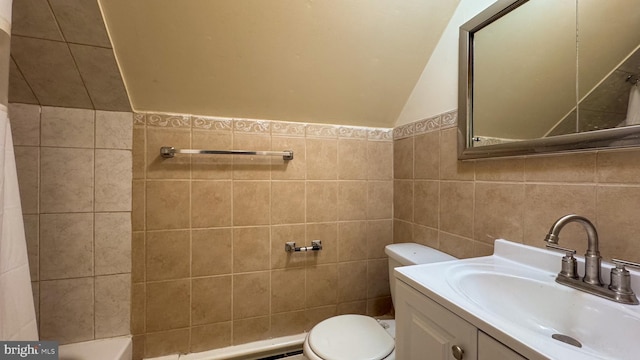 bathroom featuring vanity, toilet, tile walls, and lofted ceiling