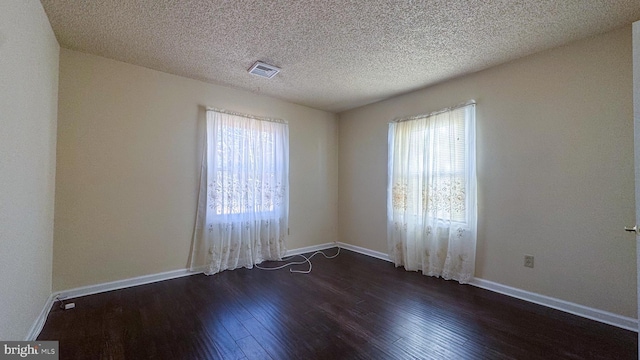 empty room featuring dark wood-type flooring and a textured ceiling