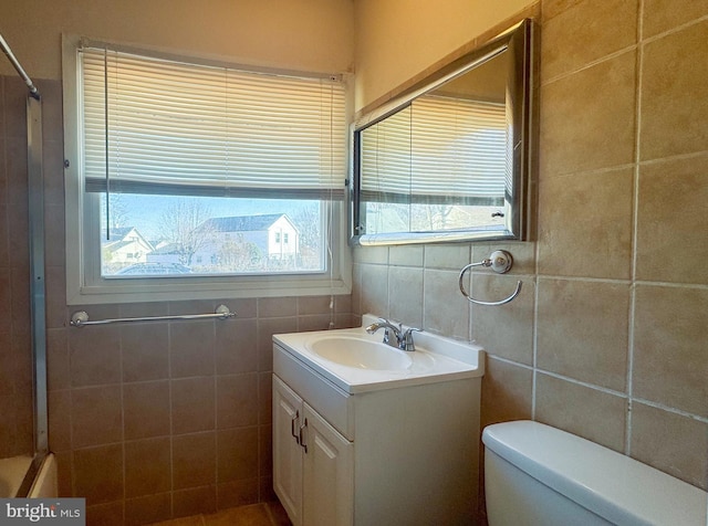 bathroom featuring walk in shower, vanity, tile walls, and toilet