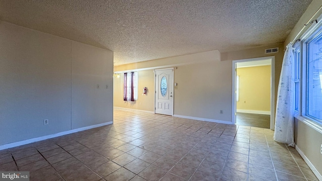 tiled empty room with a textured ceiling