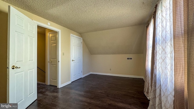 bonus room with a textured ceiling, dark wood-type flooring, and vaulted ceiling