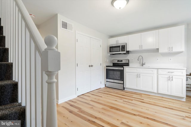 kitchen featuring sink, light wood-type flooring, white cabinetry, and stainless steel appliances