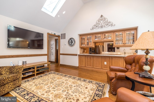 living room featuring indoor wet bar, high vaulted ceiling, and light hardwood / wood-style flooring