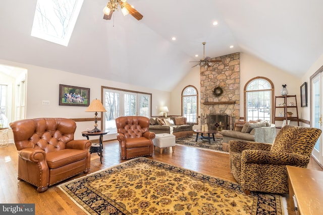 living room with ceiling fan, high vaulted ceiling, a fireplace, and light hardwood / wood-style floors