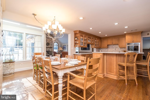 dining room featuring an inviting chandelier, wood-type flooring, vaulted ceiling, and sink