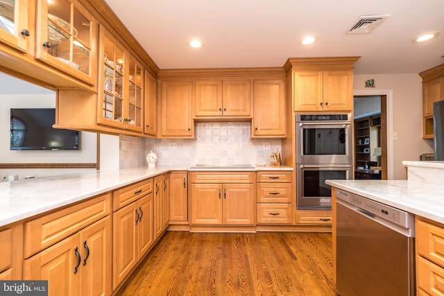 kitchen with light stone counters, appliances with stainless steel finishes, dark hardwood / wood-style flooring, and tasteful backsplash