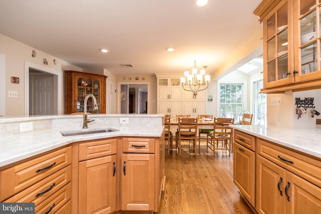 kitchen featuring hanging light fixtures, sink, an inviting chandelier, and light hardwood / wood-style flooring