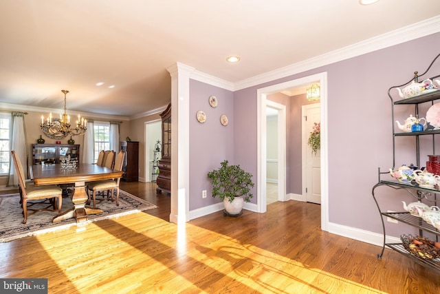 dining space with hardwood / wood-style flooring, ornamental molding, and an inviting chandelier