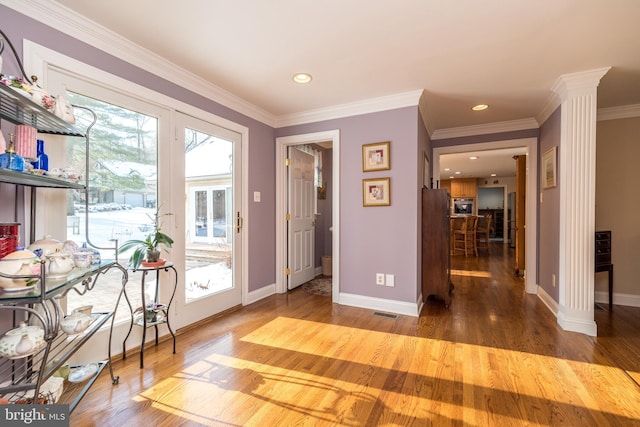 doorway to outside featuring ornamental molding, decorative columns, and hardwood / wood-style floors