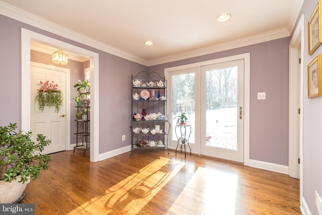 doorway to outside featuring hardwood / wood-style flooring, crown molding, and a chandelier