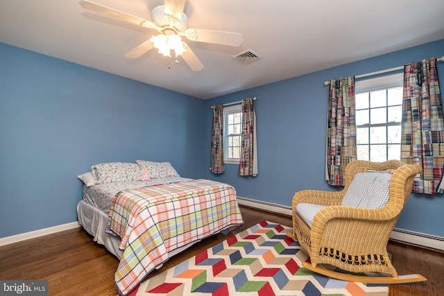 bedroom with dark hardwood / wood-style flooring, multiple windows, a baseboard radiator, and ceiling fan