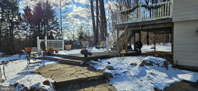 snow covered patio featuring a wooden deck