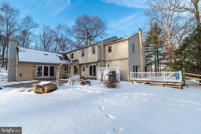 snow covered back of property featuring a wooden deck