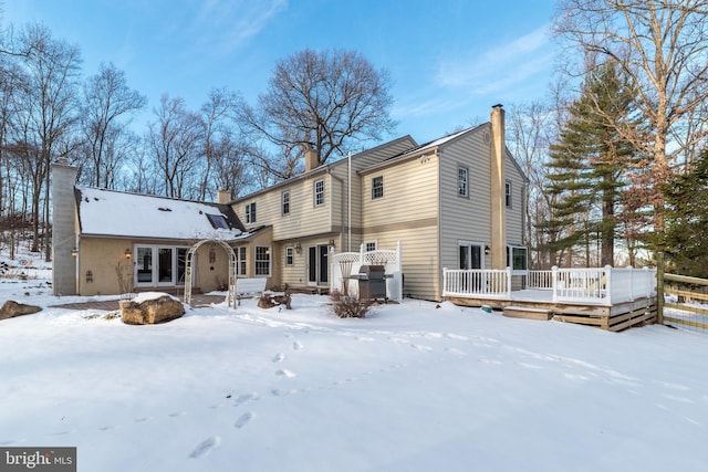 snow covered property with a wooden deck and french doors