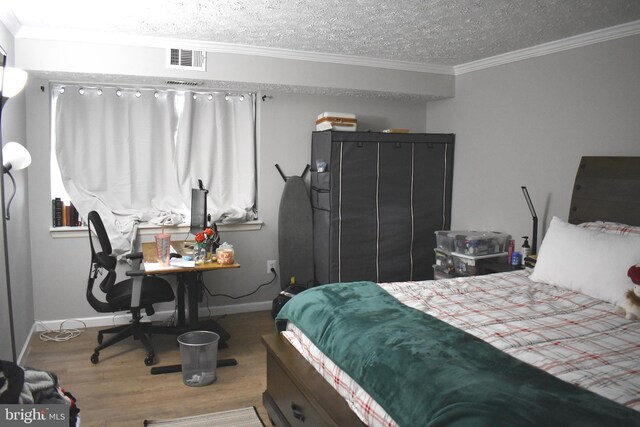 bedroom with wood-type flooring, a textured ceiling, and crown molding