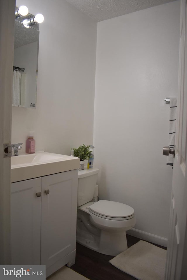 bathroom featuring vanity, toilet, wood-type flooring, and a textured ceiling