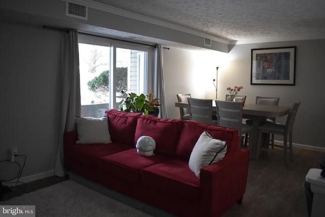 living room featuring crown molding, dark wood-type flooring, and a textured ceiling