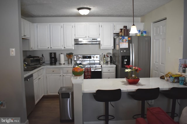 kitchen with dark wood-type flooring, hanging light fixtures, a textured ceiling, white cabinetry, and stainless steel appliances